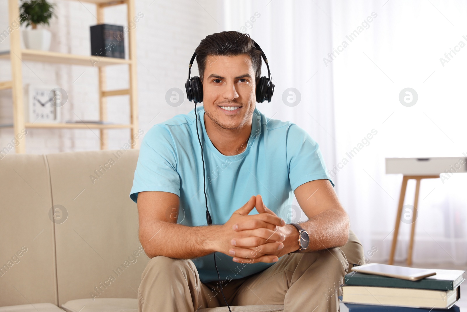 Photo of Man listening to audiobook on sofa at home