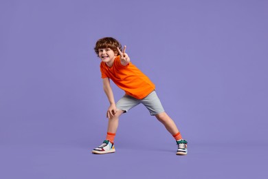 Photo of Happy little boy dancing on violet background