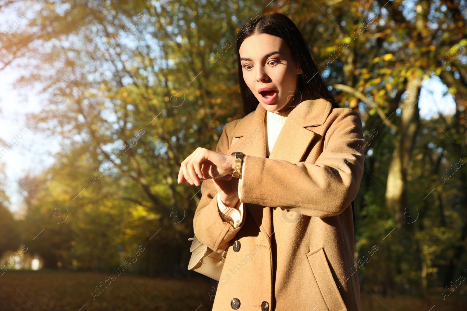 Photo of Emotional woman checking time on watch in park. Being late concept