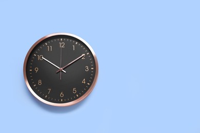 Stylish round clock on light blue background, top view with space for text. Interior element