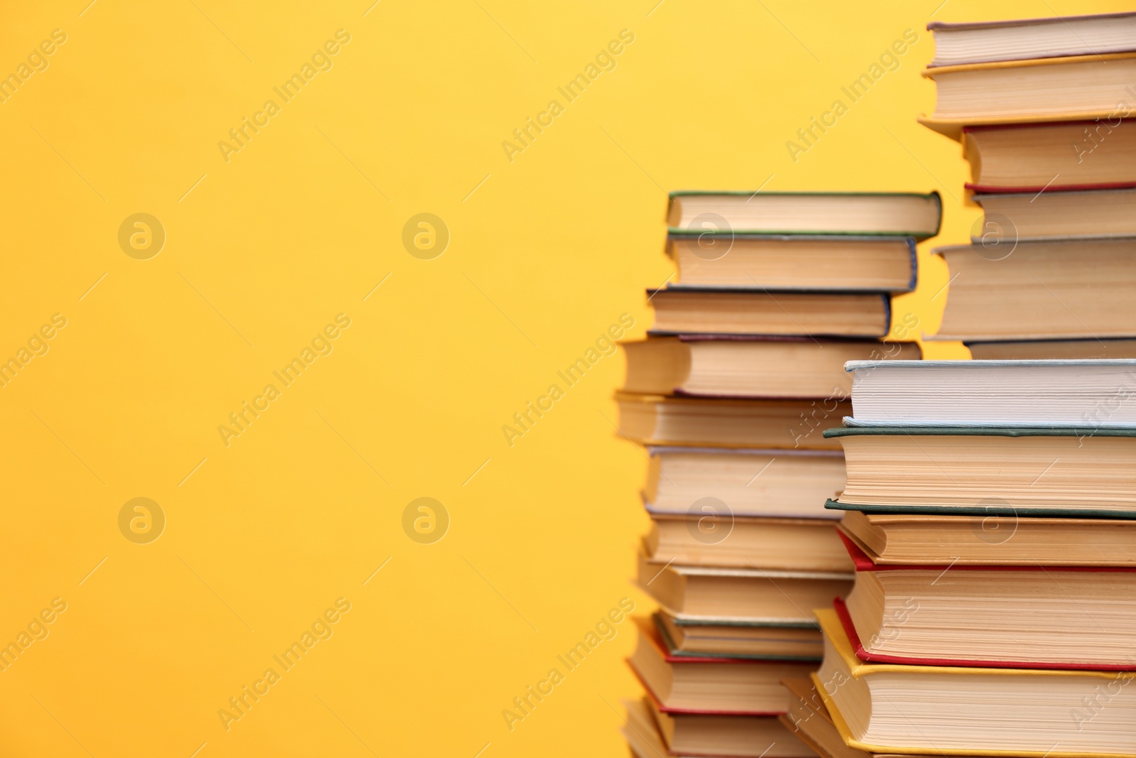 Photo of Many hardcover books on orange background, space for text. Library material