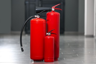 Photo of Three new red fire extinguishers in hall