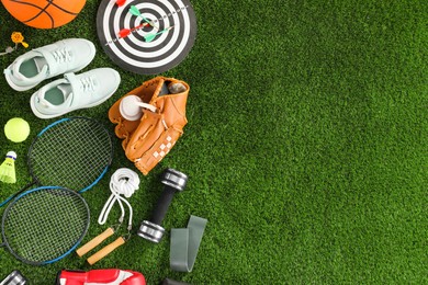 Photo of Different sport equipment and sneakers on green grass, flat lay. Space for text