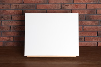 Wooden easel with blank canvas on table