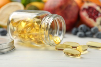 Photo of Vitamin pills, bottle and fresh fruits on white wooden table, closeup