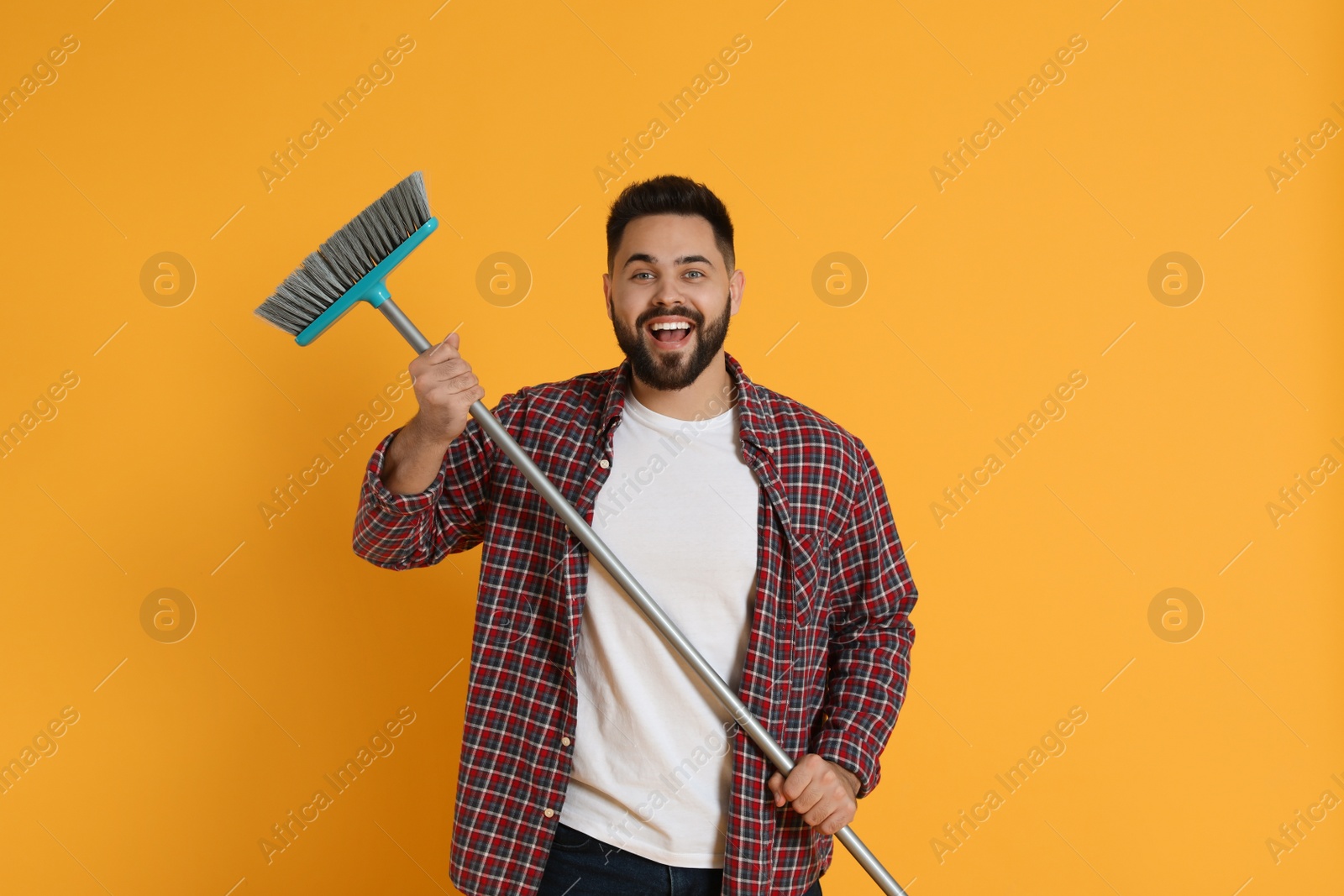 Photo of Young man with broom on orange background