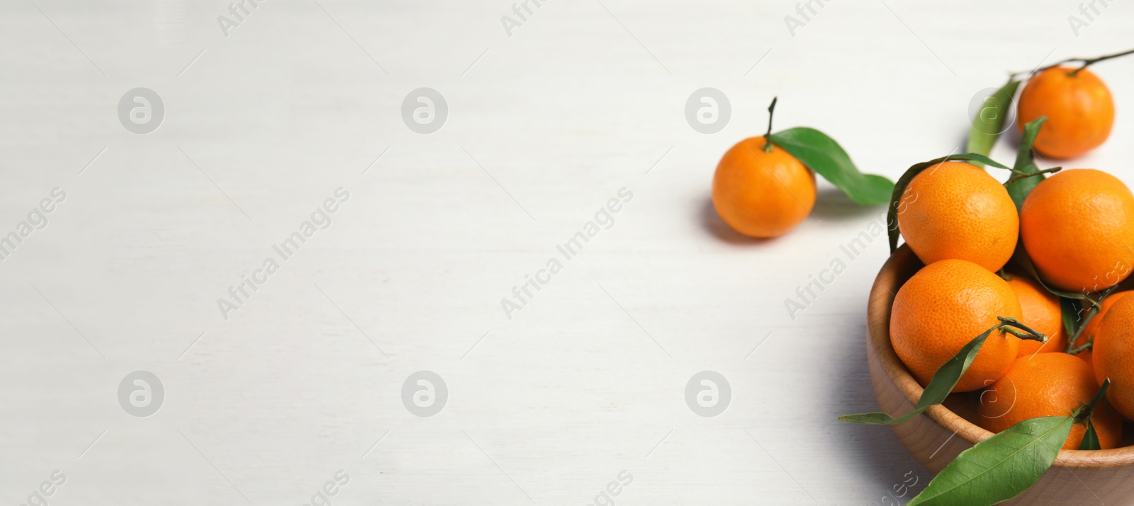 Image of Fresh ripe tangerines in bowl on white table, space for text. Banner design