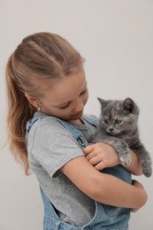 Photo of Cute little girl with kitten on light background. Childhood pet