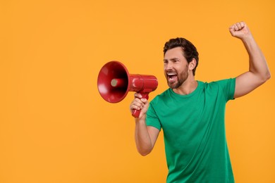 Photo of Emotional sports fan with megaphone on orange background, space for text