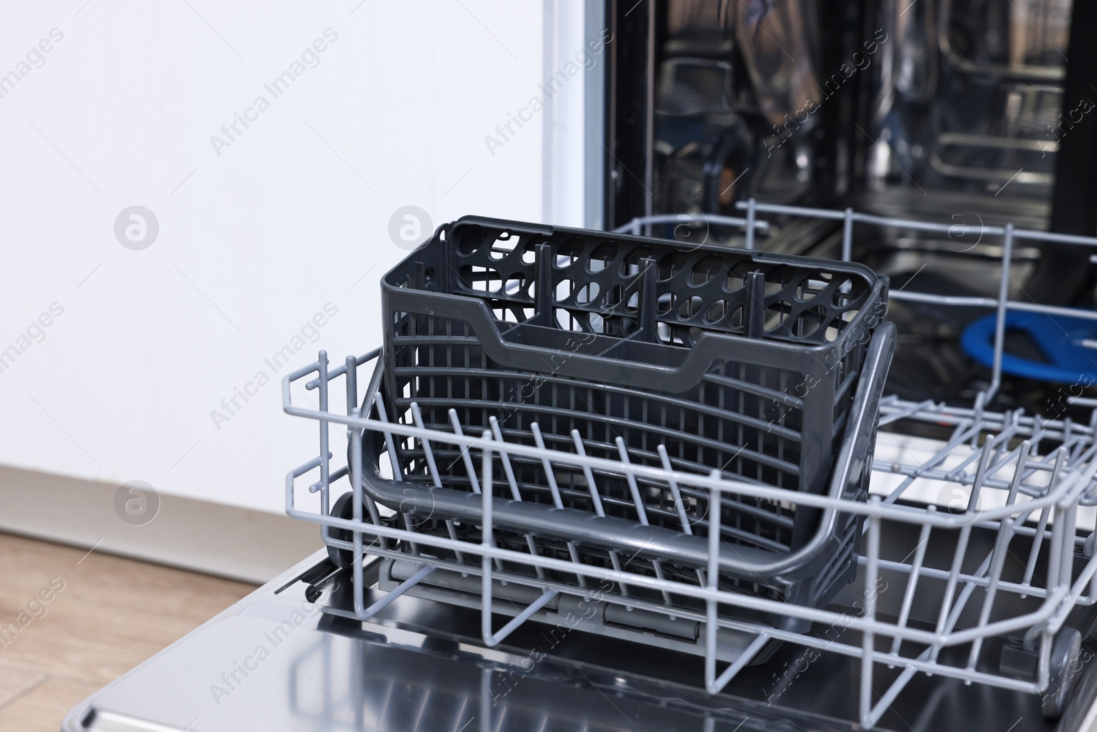 Photo of Open clean empty dishwasher in kitchen, closeup. Home appliance