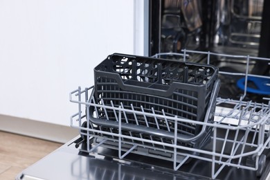 Photo of Open clean empty dishwasher in kitchen, closeup. Home appliance