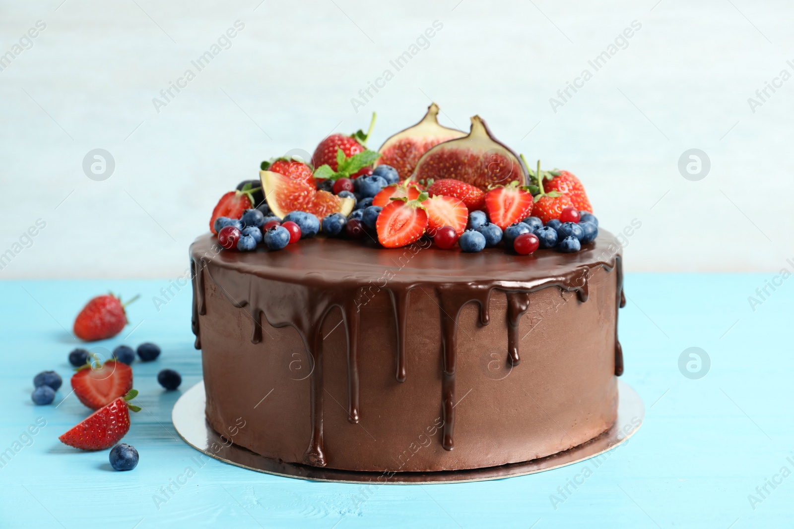 Photo of Fresh delicious homemade chocolate cake with berries on table against light background