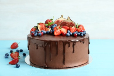 Photo of Fresh delicious homemade chocolate cake with berries on table against light background