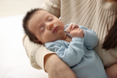 Mother with her sleeping newborn baby on light background, closeup