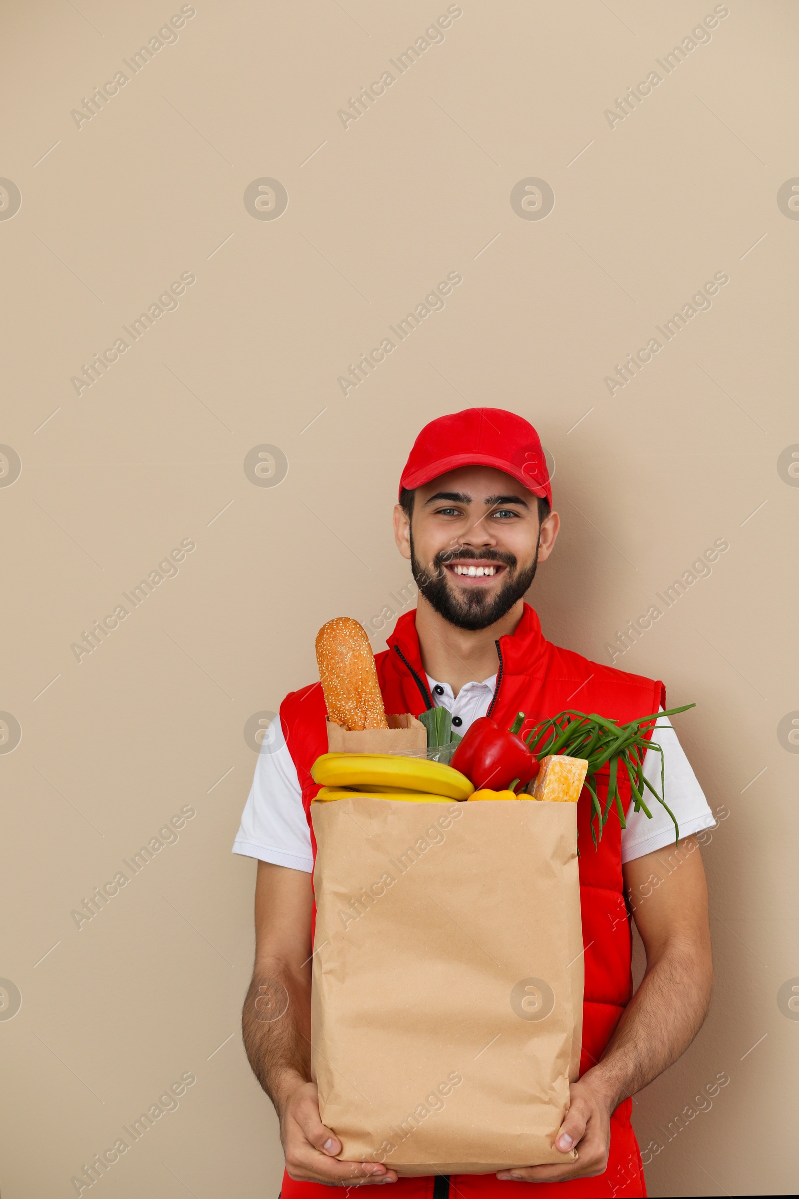 Photo of Man holding paper bag with fresh products on color background. Food delivery service