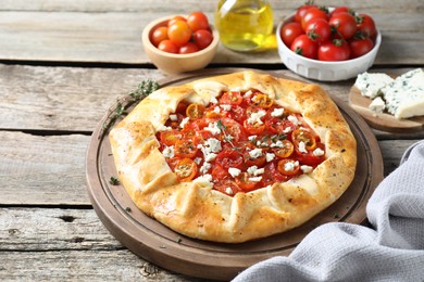 Photo of Tasty galette with tomato, thyme and cheese (Caprese galette) on wooden table, closeup. Space for text