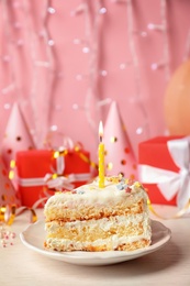 Photo of Slice of delicious birthday cake with candle on table