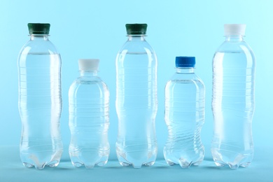 Row of different plastic bottles with water on color background