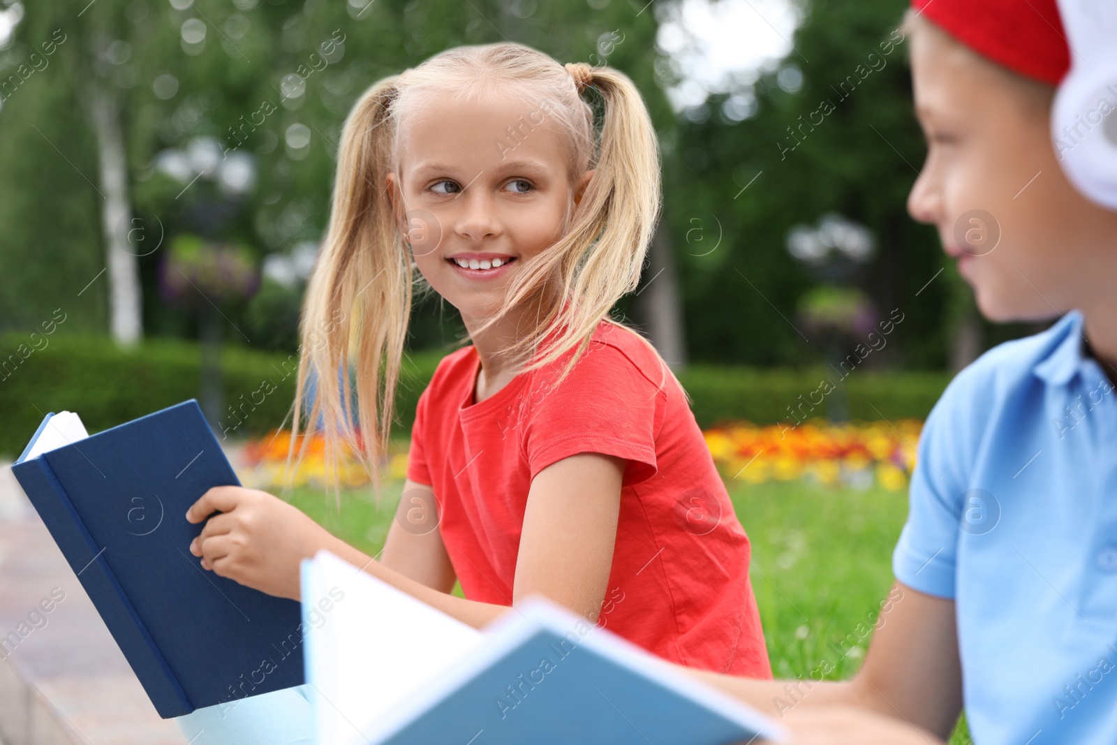 Photo of Cute boy in headphones and girl reading books in green park