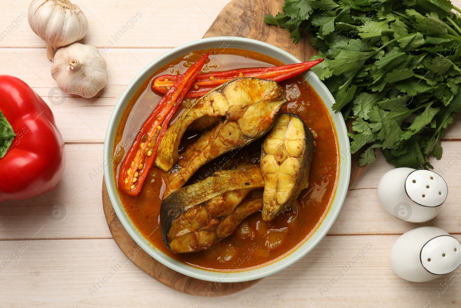 Photo of Tasty fish curry and ingredients on white wooden table, flat lay. Indian cuisine