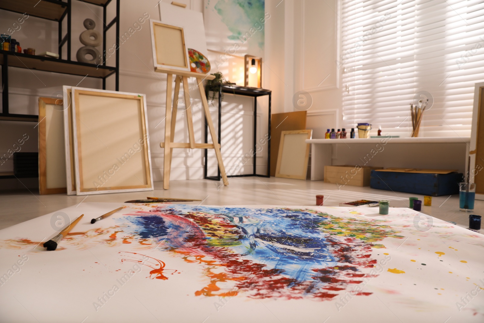 Photo of Wooden easel and abstract picture in art studio