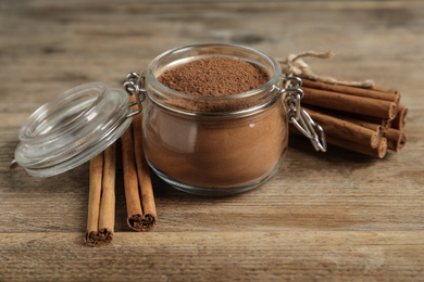 Aromatic cinnamon powder and sticks on wooden table