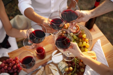 Photo of Friends holding glasses of wine at table, closeup