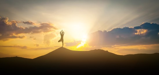 Image of Silhouette of woman practicing yoga under beautiful sky at sunset, banner design