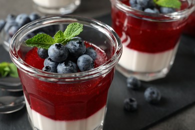 Photo of Delicious panna cotta with fruit coulis and fresh blueberries on table, closeup