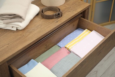 Photo of Chest of drawers with different folded clothes and belt indoors
