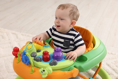 Portrait of cute baby with toy walker indoors. Learning to walk