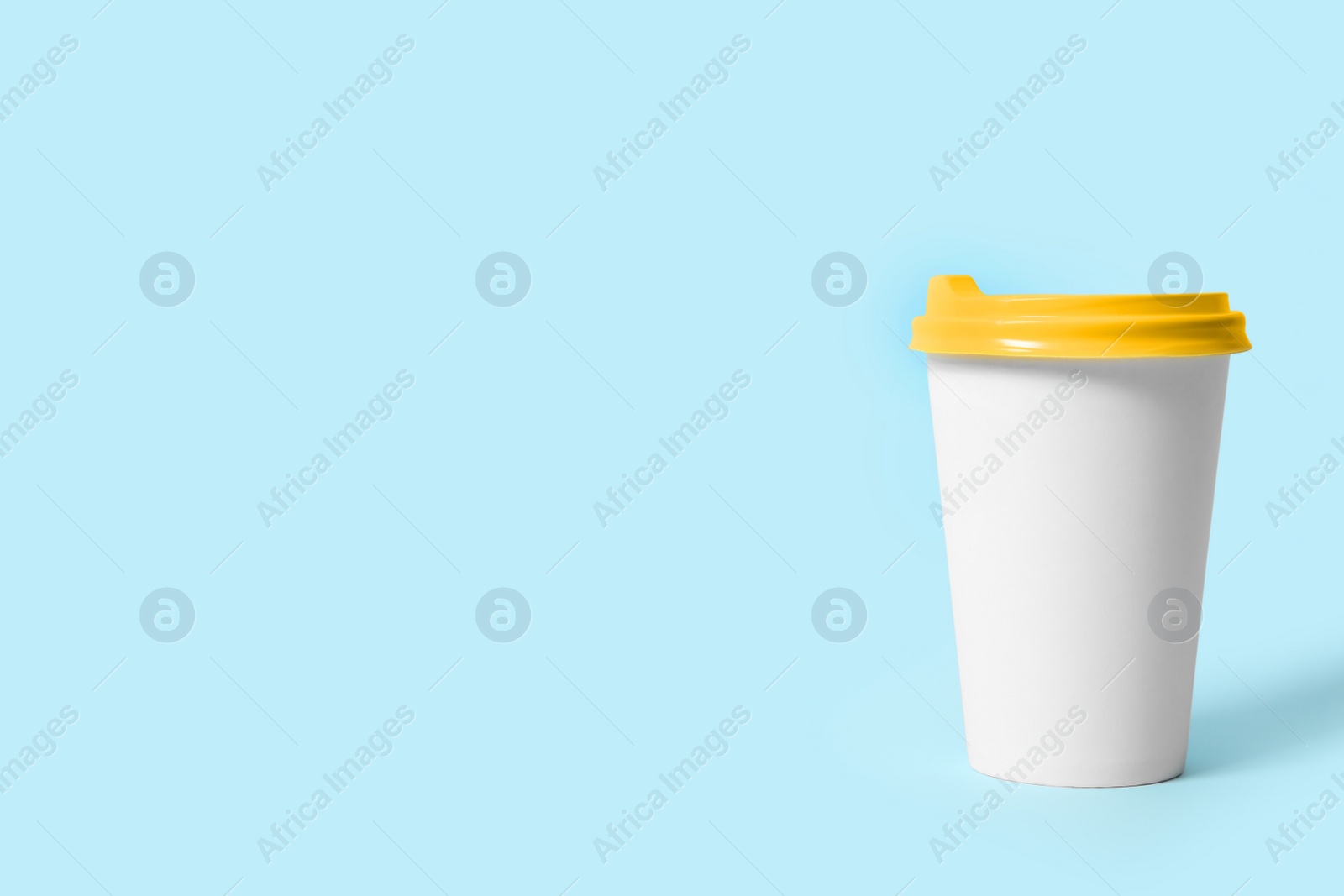 Photo of Takeaway paper coffee cup on light blue background. Space for text