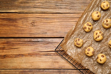 Photo of Unbaked chocolate chip cookies on wooden table, top view. Space for text