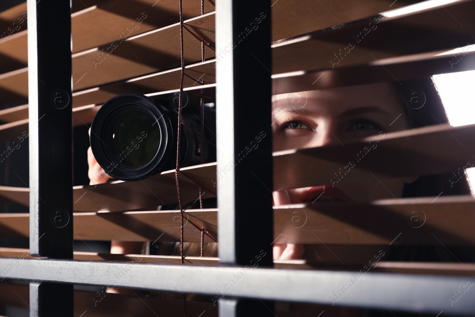 Photo of Private detective with camera spying near window indoors, closeup