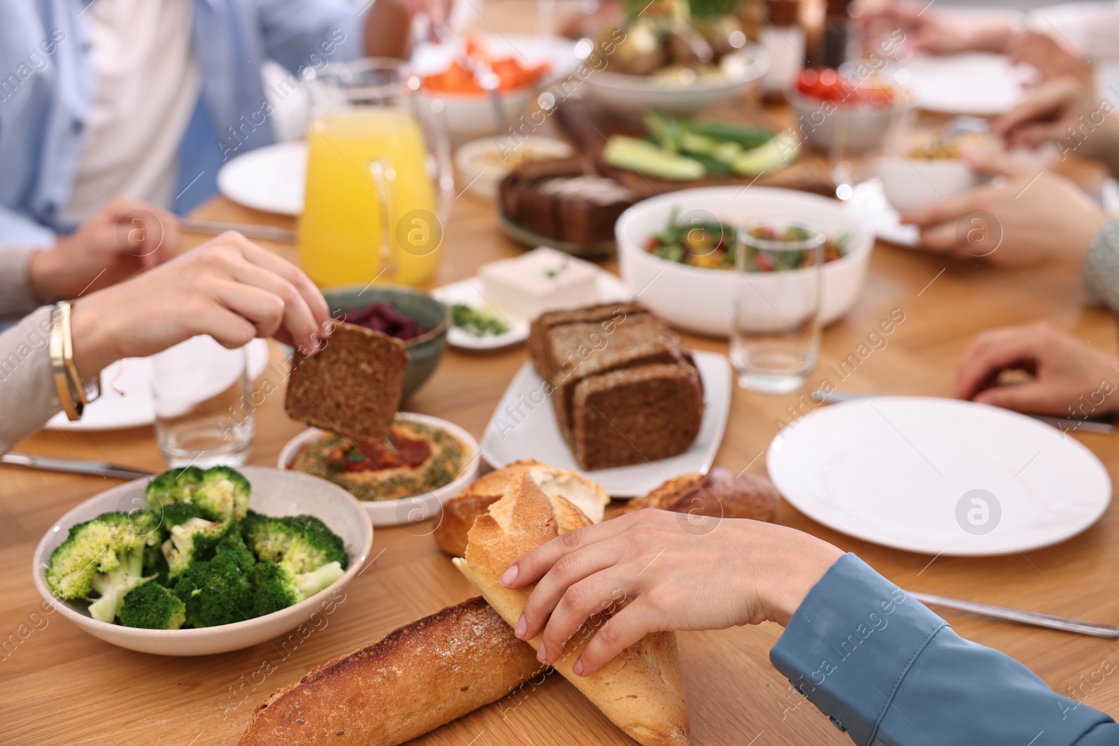 Photo of Friends eating vegetarian food at wooden table indoors, closeup