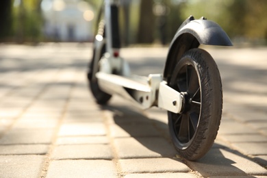 Photo of Modern kick scooter outdoors on sunny day, closeup. Space for text