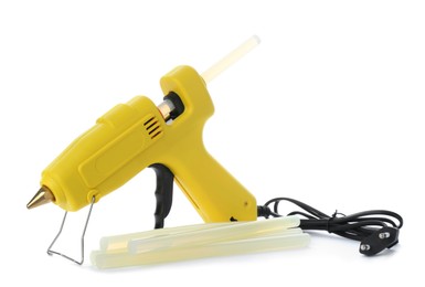 Yellow glue gun and sticks on white background