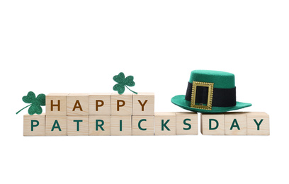 Leprechaun hat, clover leaves and wooden cubes with phrase SAINT PATRICK'S DAY on white background