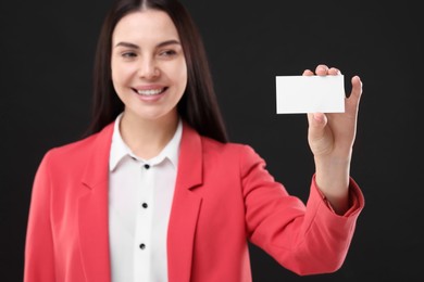 Photo of Happy woman holding blank business card on black background, selective focus