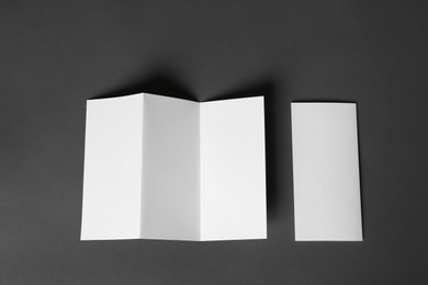 Photo of Two blank brochures on dark grey background, flat lay. Mock up for design