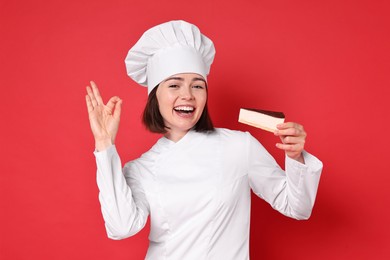 Happy confectioner with cheesecake showing ok gesture on red background