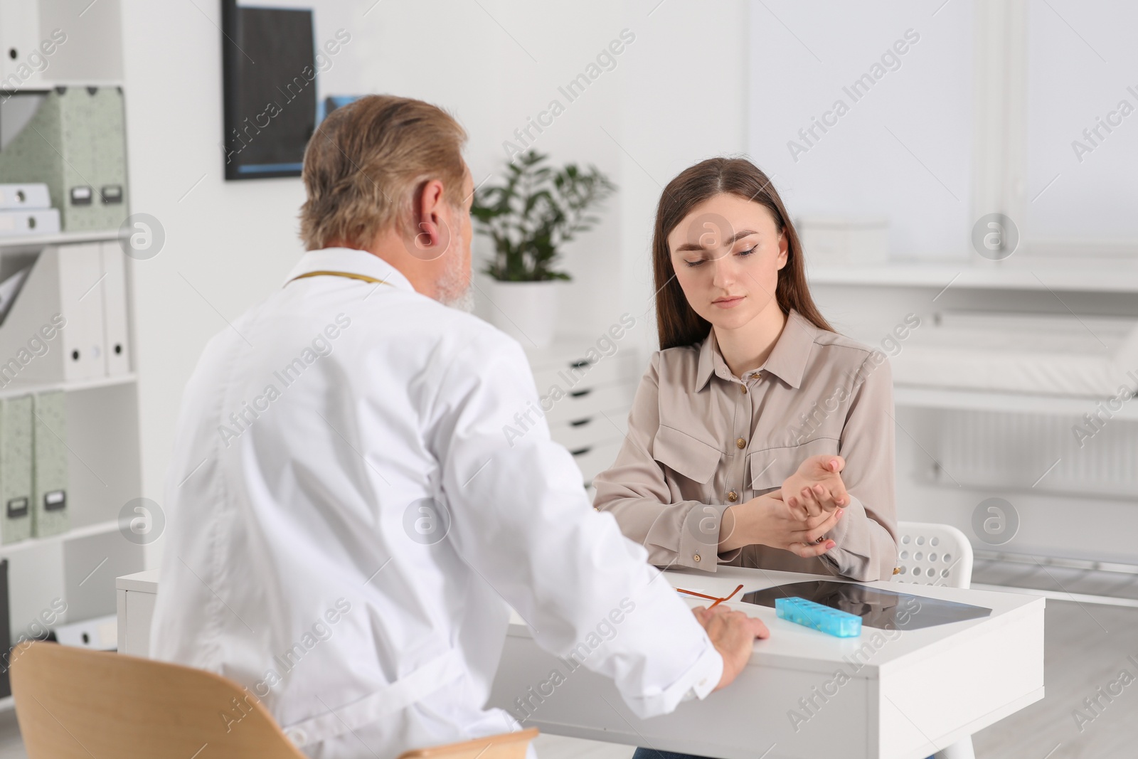 Photo of Orthopedist examining patient with injured hand in clinic