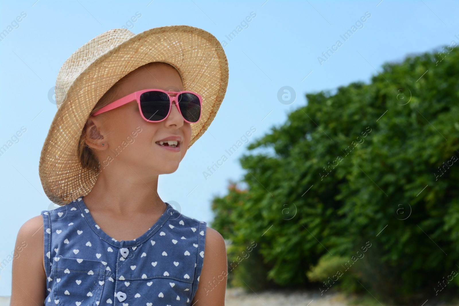 Photo of Little girl wearing sunglasses and hat at beach on sunny day. Space for text