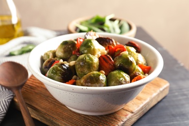 Photo of Bowl of warm salad with Brussels sprouts and carrots on table