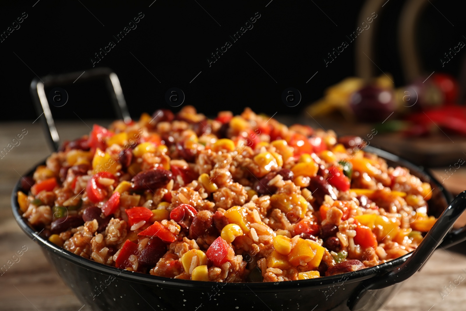 Photo of Pan with tasty chili con carne on wooden table, closeup