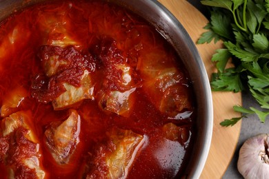Photo of Delicious stuffed cabbage rolls cooked with homemade tomato sauce in pot on table, top view