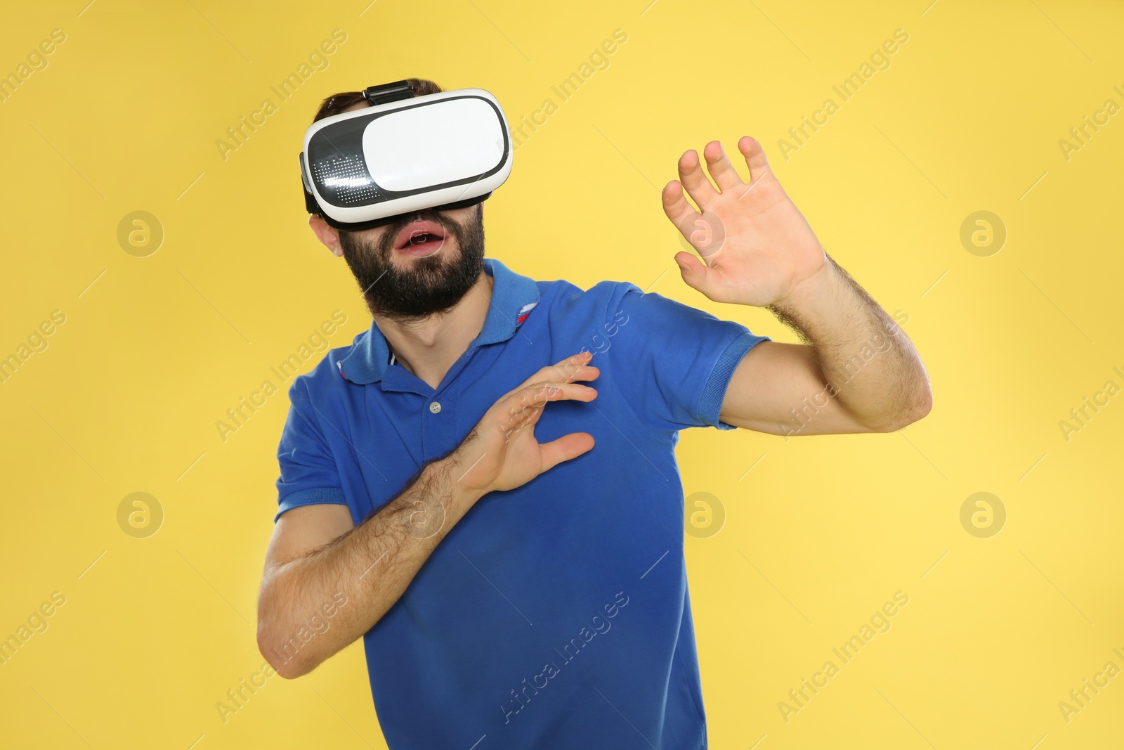 Photo of Emotional young man playing video games with virtual reality headset on color background