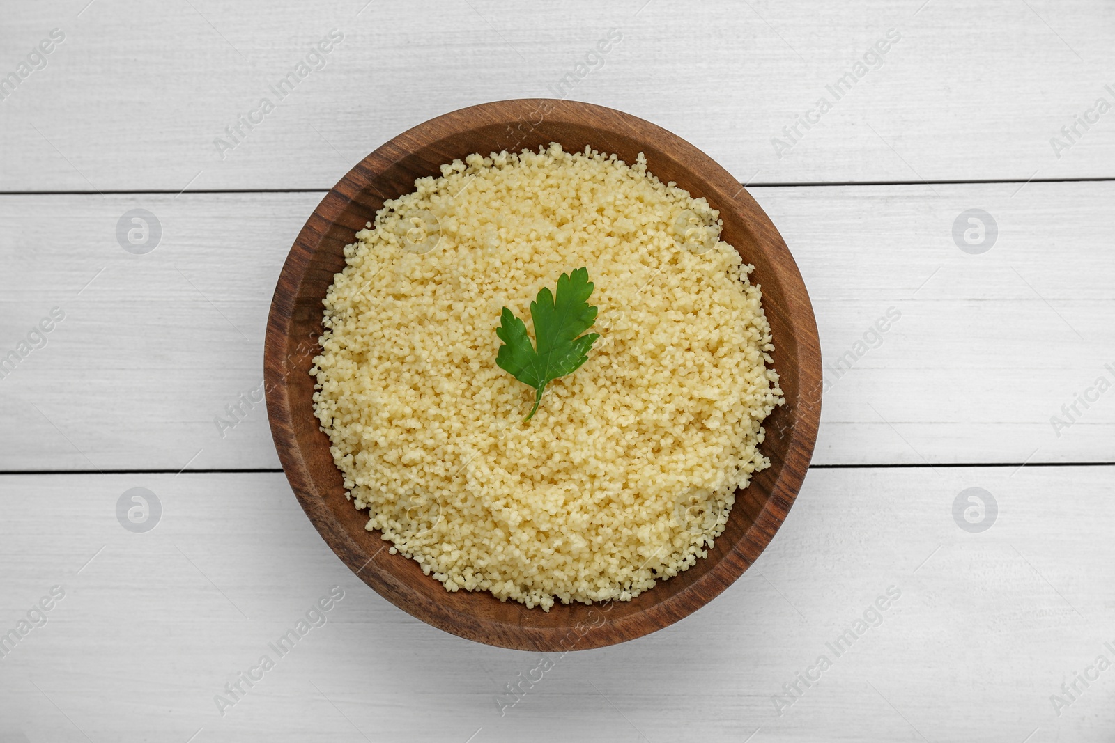 Photo of Tasty couscous with parsley on white wooden table, top view