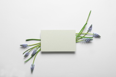 Beautiful spring muscari flowers and card on light background, flat lay. Space for text