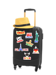Image of Modern suitcase with travel stickers and hat on white background